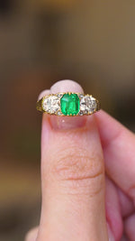 An antique, Victorian green emerald and diamond three-stone ring shown in video held between fingers.