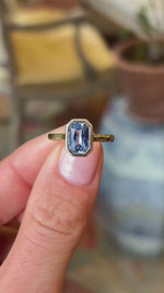 A video showing an Antique-inspired pale blue sapphire solitaire engagement ring in yellow gold held between fingers.