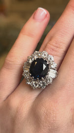 Vintage 1960s sapphire and diamond cluster ring shown on hand.