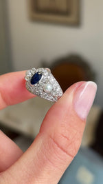 Close up video of a white gold Antique, Belle Époque sapphire, pearl and diamond cluster cocktail ring held by two finger and rotated slowly 