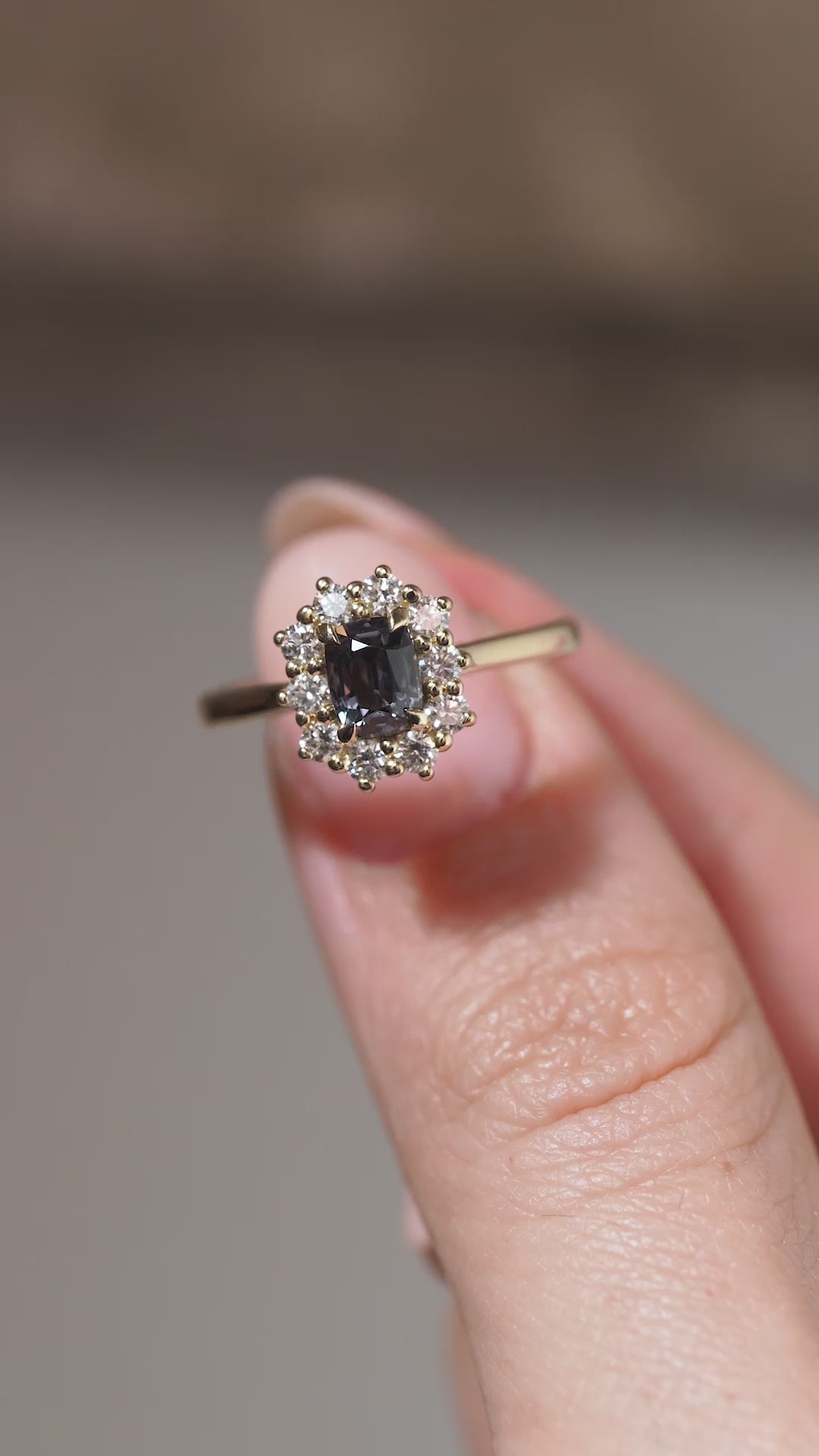 A close-up video of the sapphire engagement ring held between fingers, showcasing the gemstone's facets and intricate diamond setting.