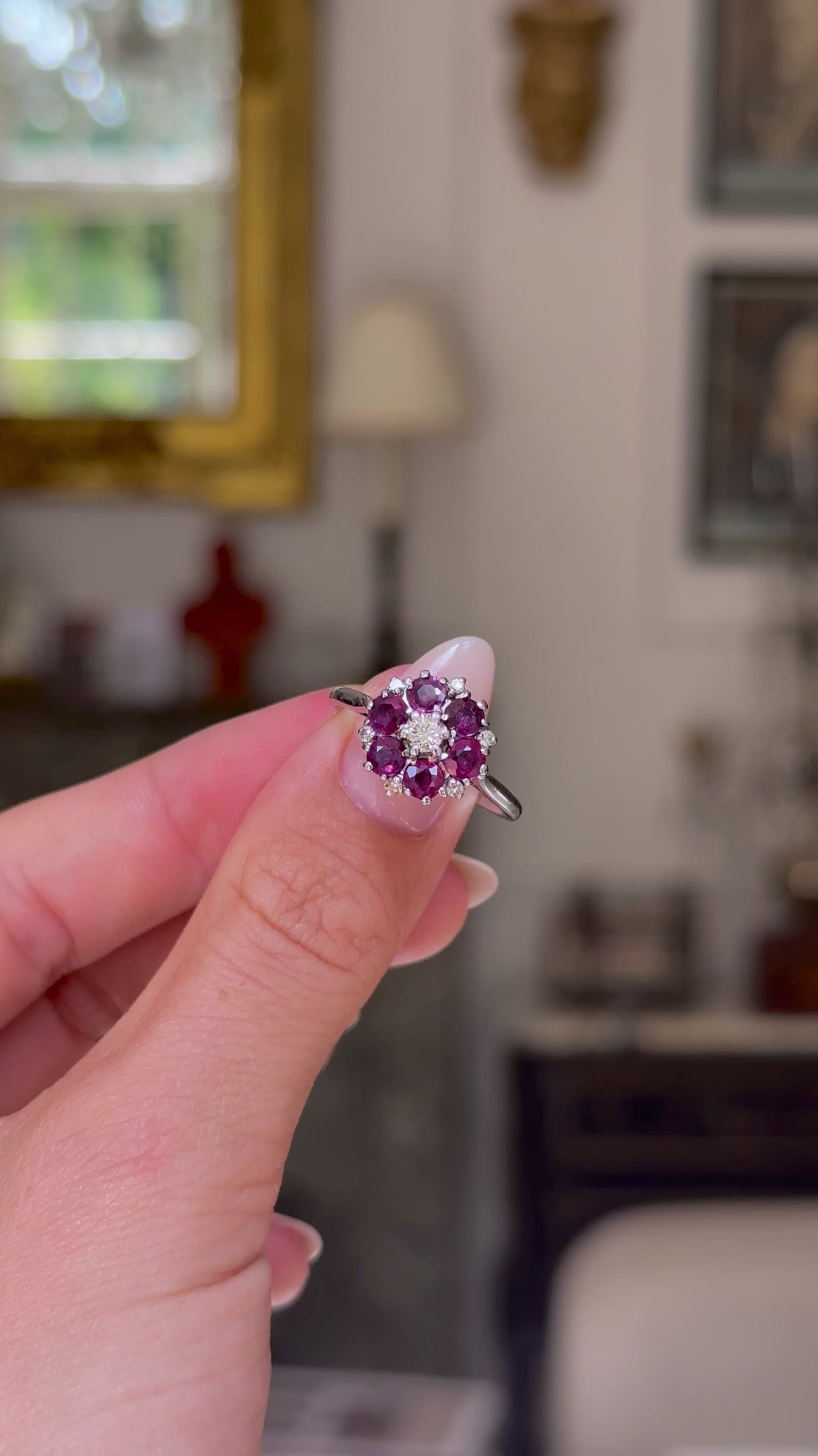 ruby and diamond cluster ring, held in fingers and rotated  to give perspective. 