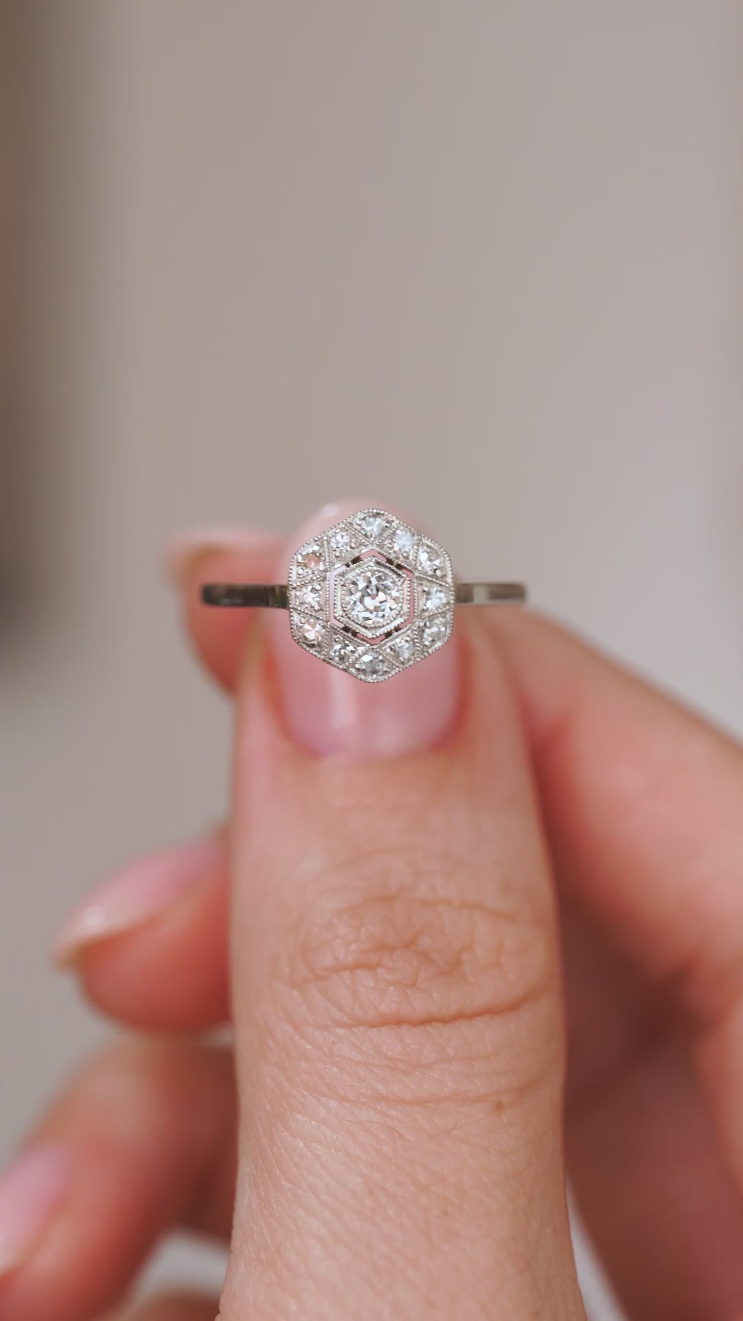 Video close-up of the Art Deco engagement ring balanced on a fingertip, highlighting the old-cut centre diamond and milgrain detail.