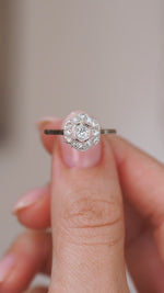 Video close-up of the Art Deco engagement ring balanced on a fingertip, highlighting the old-cut centre diamond and milgrain detail.