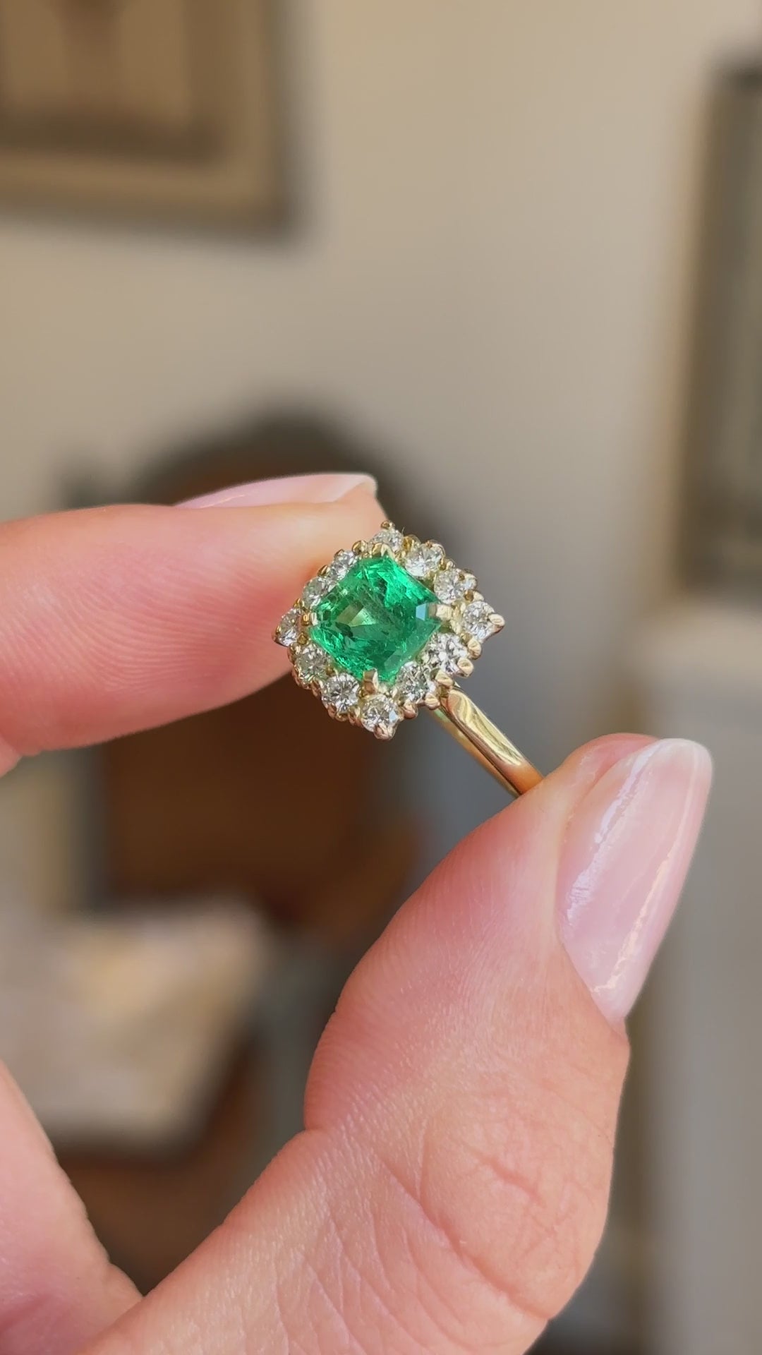 Vintage 1980s Colombian emerald and diamond cluster engagement ring showcasing an emerald-cut Colombian emerald and diamond halo, held by hand to highlight the setting and craftsmanship.