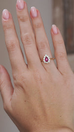 Video of the pear-cut ruby cluster ring on the hand, capturing the sparkle of its diamond surround.