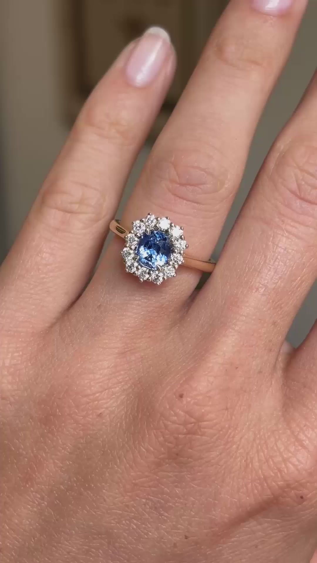 A video showing an engagement ring with an Antique-inspired, blue sapphire and diamond halo worn on a finger.