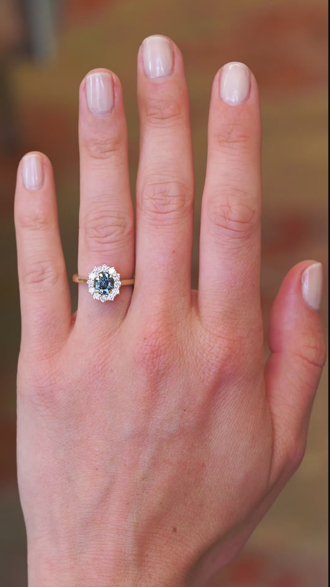 Teal sapphire cluster ring worn on hand showing colour shift and natural movement.