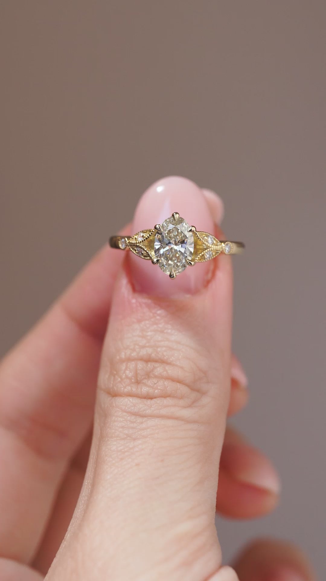 A close-up video of the pale yellow diamond ring balanced on a fingertip.