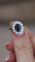 A close-up video of the vintage sapphire ring held between fingers, showcasing the gemstone's rich blue tones and intricate diamond halo.