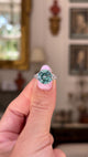 Art deco blue zircon and diamond ring, held in hand and rotated to give perspective, front view. 