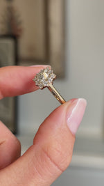 Close up video of a yellow gold Antique-inspired, princess-cut diamond cluster engagement ring held between two fingers and rotated slowly to showcase the diamonds.