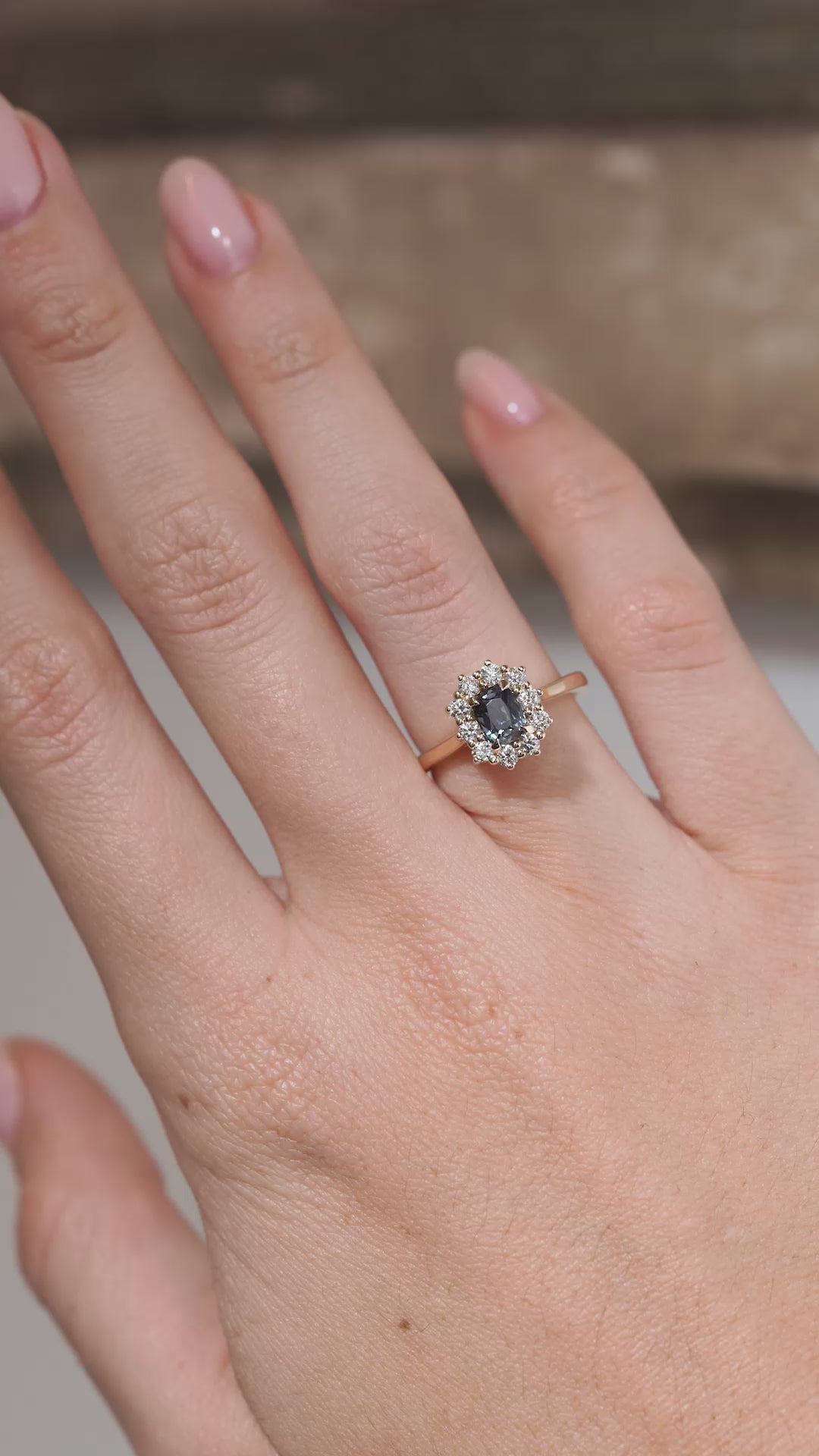 A video of the sapphire cluster ring worn on a finger, capturing the gemstone's dark blue tones and sparkling diamond surround.