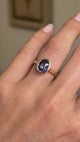 A close-up video of an antique-inspired, royal purple oval sapphire solitaire ring in yellow gold shown on a hand.