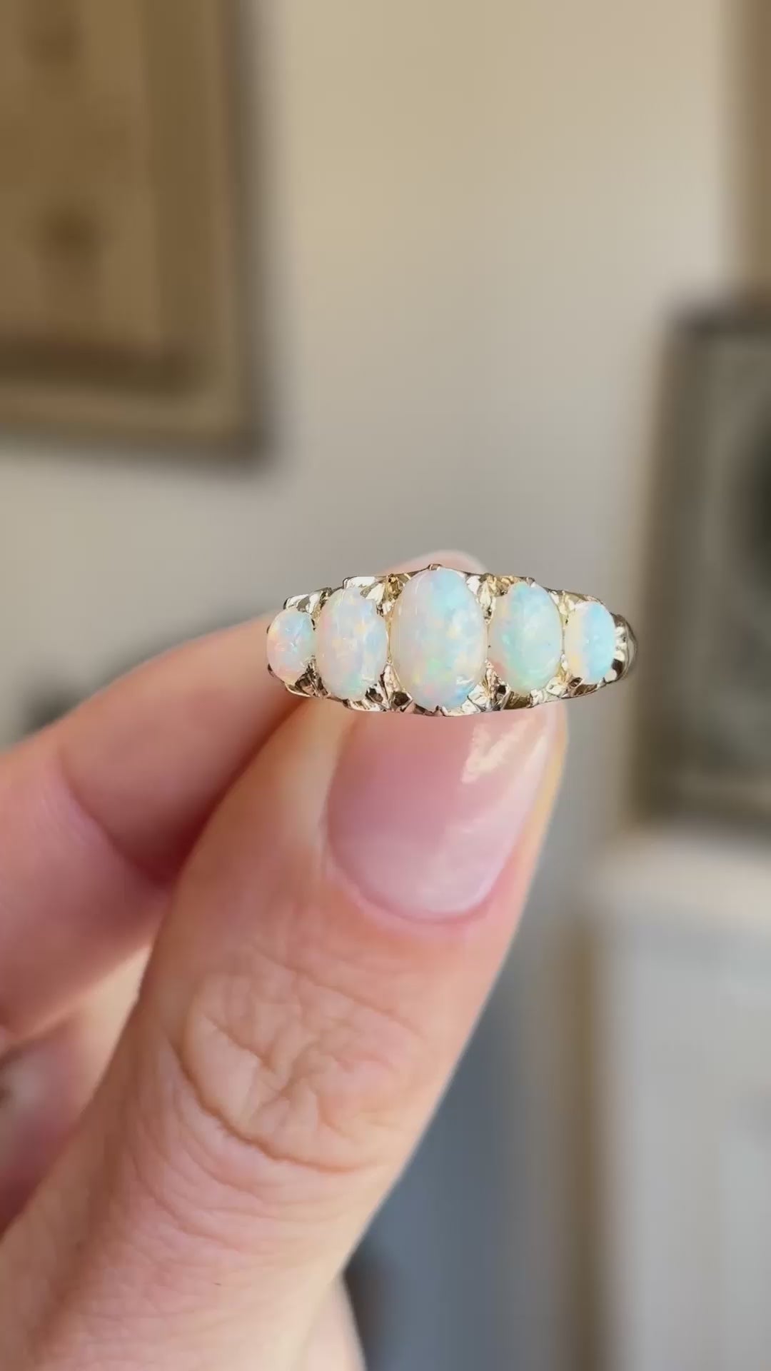 A Victorian Australian precious opal five-stone ring held between fingers showing the ring details in video.