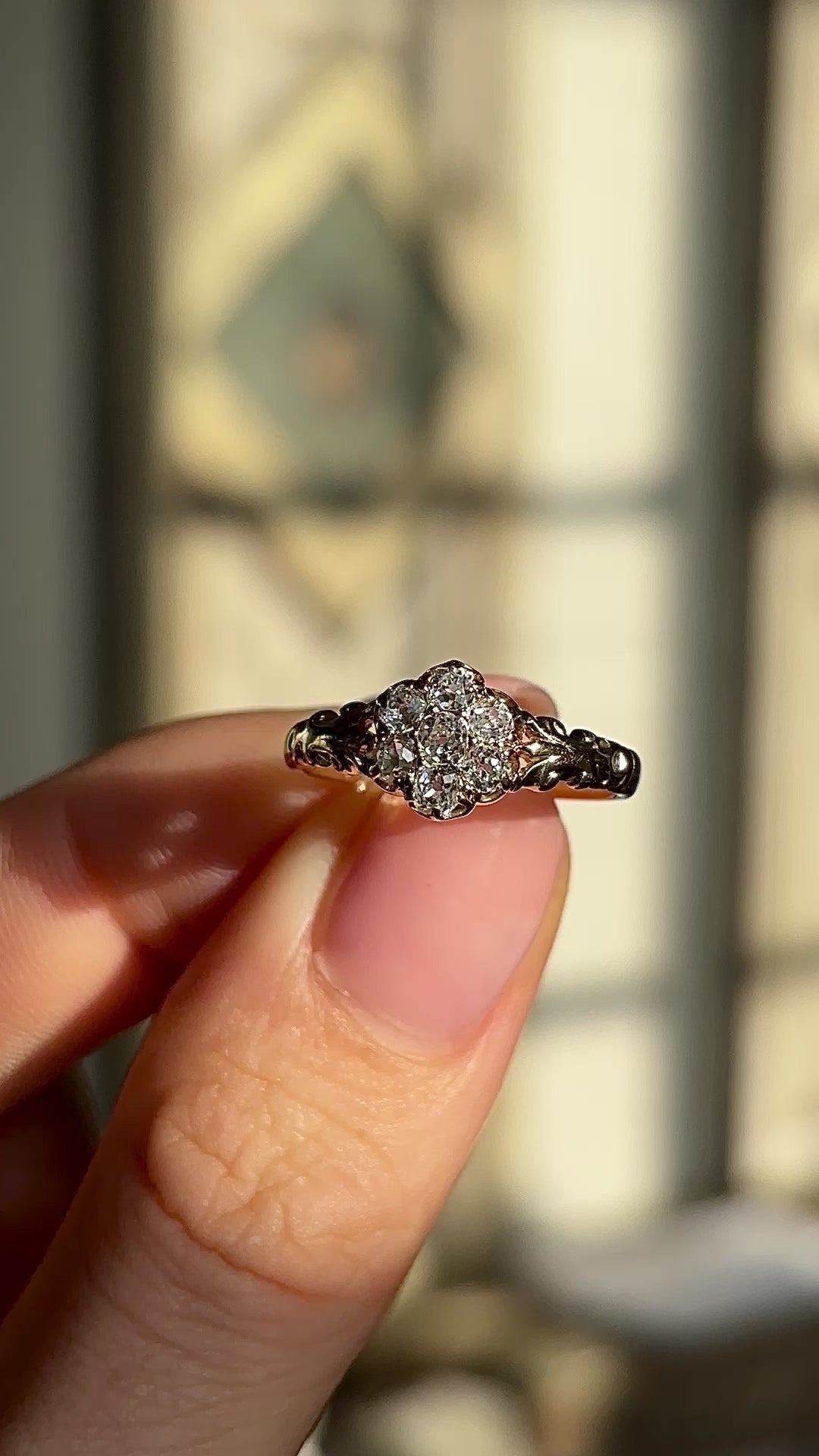2093-Antique, Edwardian diamond daisy cluster ring held in fingers