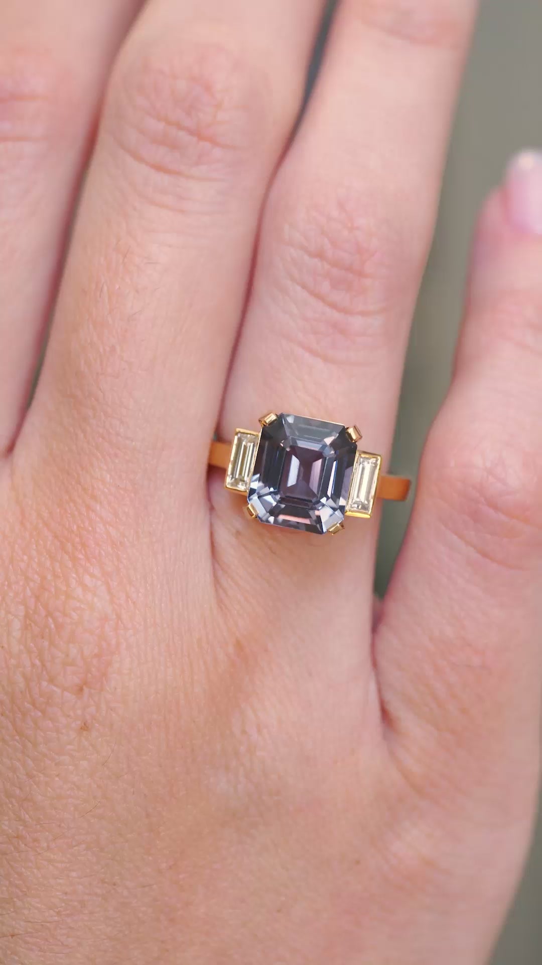 A video of a Blue spinel three-stone engagement ring shown at full scale on the hand.