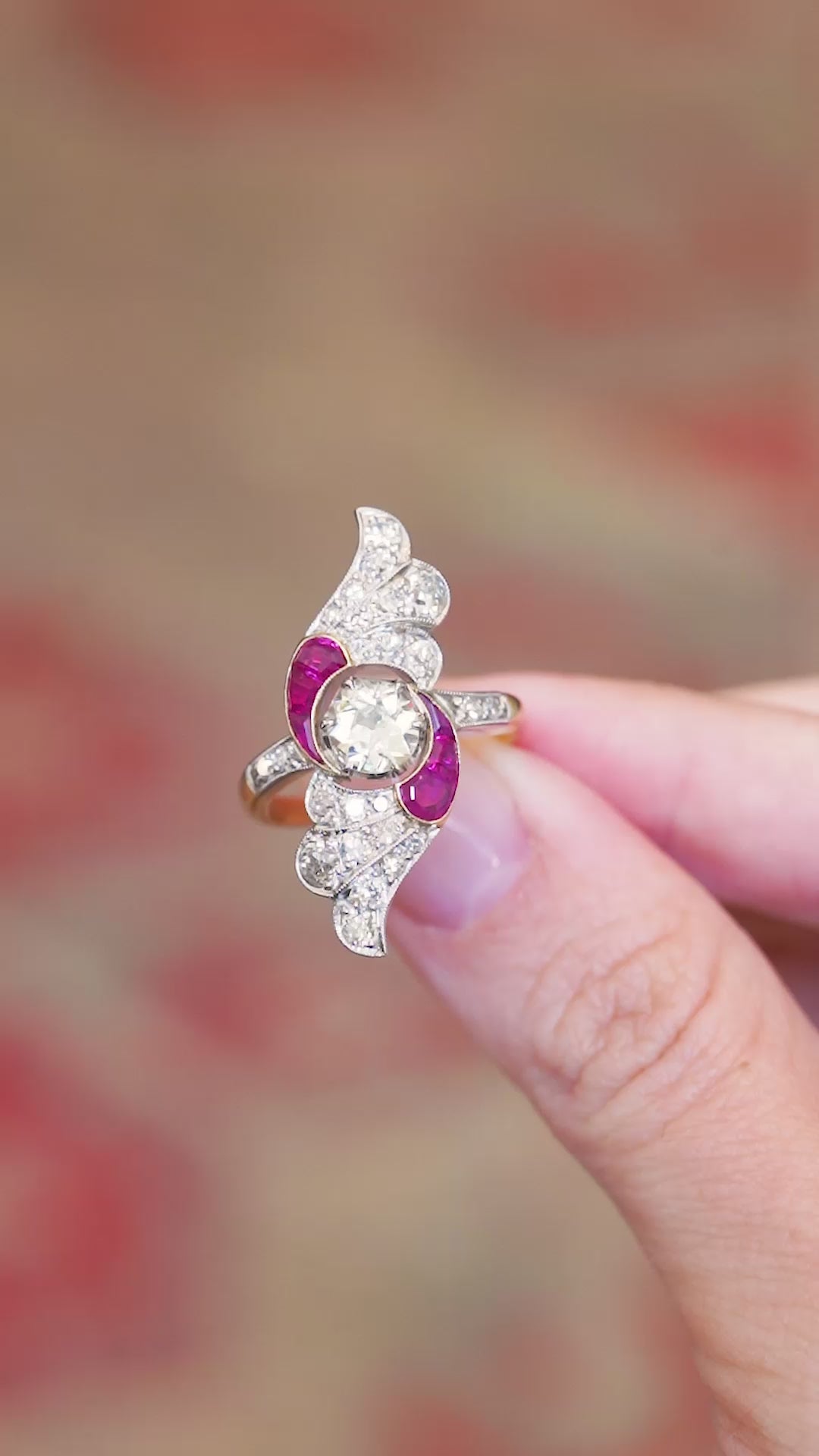 Diamond and ruby cocktail ring shown in close detail with sculptural flowing design.
