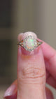 A video showing the details of an antique, Edwardian gold ring, featuring an oval opal with a diamond halo.