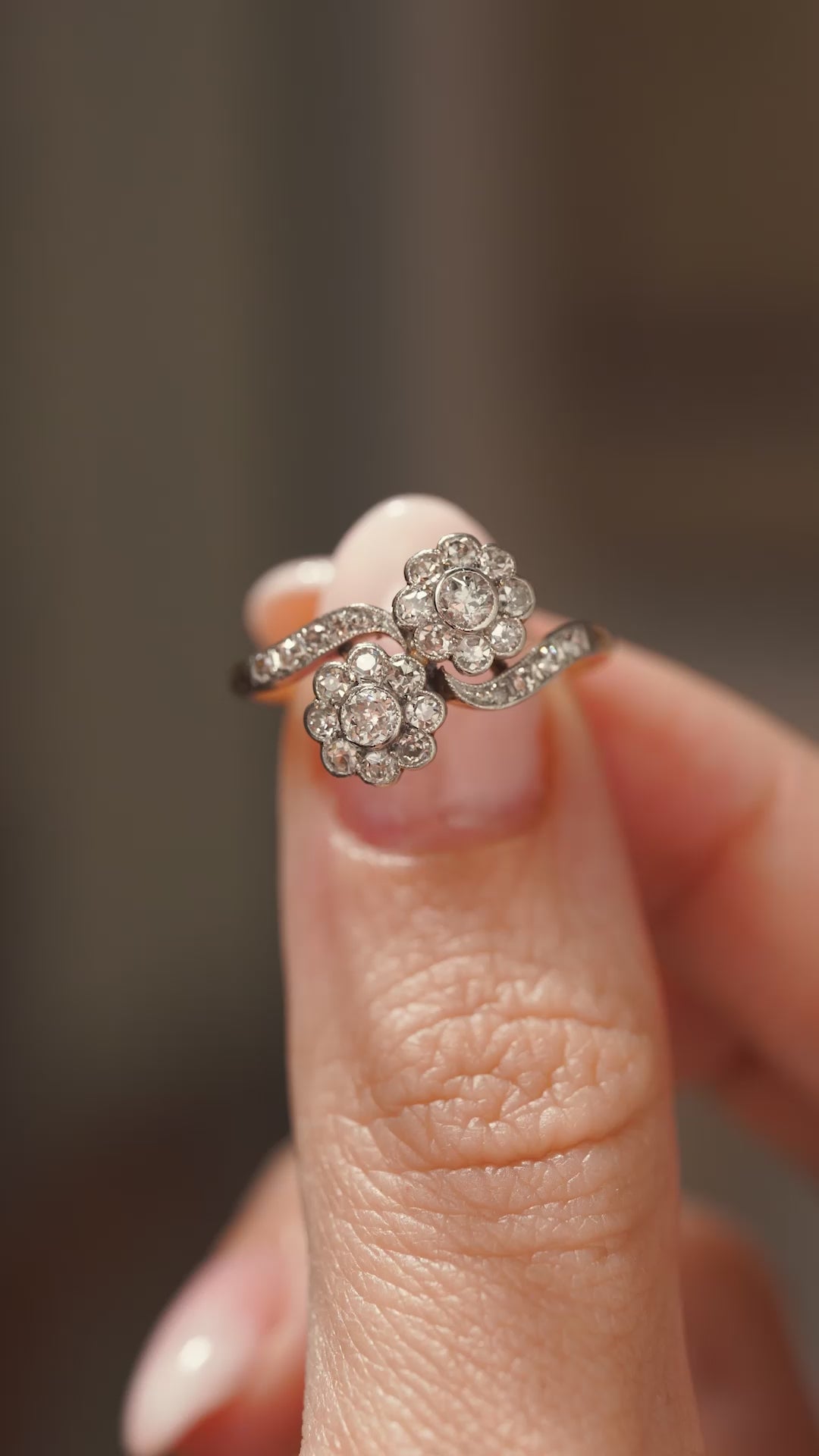 A video of a yellow gold antique Edwardian diamond two stone engagement ring held in between fingers and turned to show off different angles.
