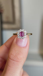 Close-up video of an antique-inspired yellow gold cluster ring showcasing a step-cut pinkish-red ruby framed by sparkling diamonds, highlighting colour, brilliance and refined craftsmanship.