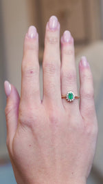 Vintage 1980s emerald and diamond cluster ring worn on hand with oval emerald and diamond halo.