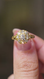 A video of a Victorian yellow gold engagement ring designed as a diamond cluster held in between the thumb and finger, turned and rotated to show off different angles of the ring. 
