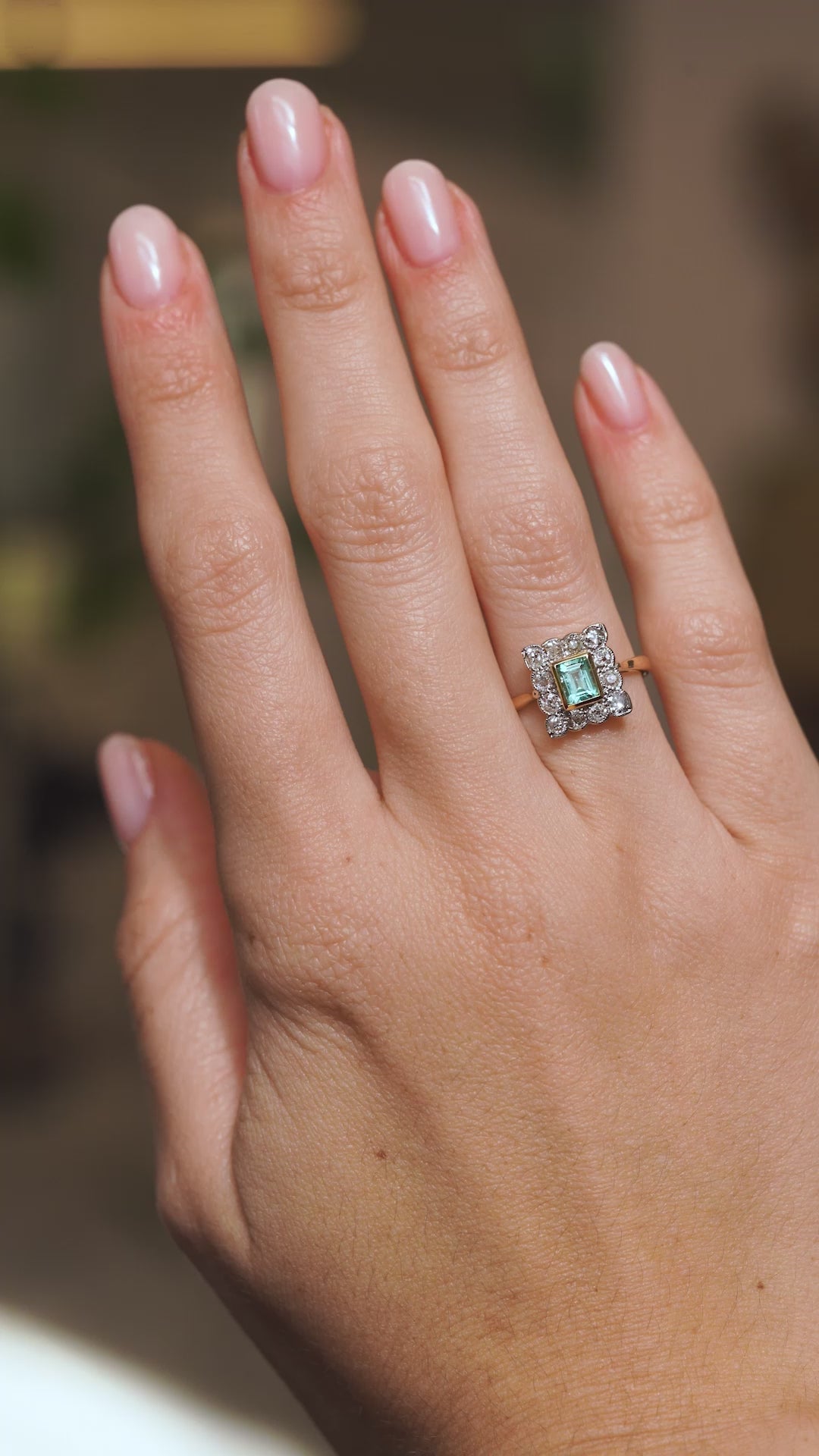 Video of an antique Edwardian emerald cluster ring worn on the hand, capturing the pale green gemstone and old-mine diamond sparkle.