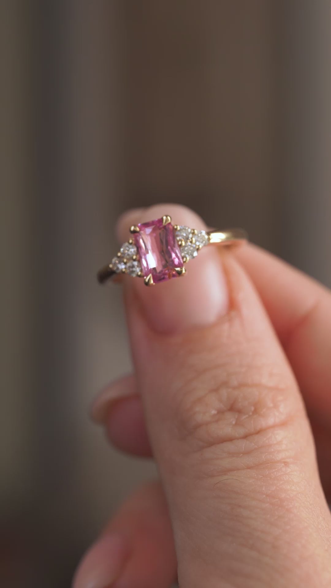 Video presenting the vintage-inspired engagement ring balanced on a fingertip for a clear view of its pink sapphire and trefoil setting.