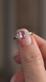 Video presenting the vintage-inspired engagement ring balanced on a fingertip for a clear view of its pink sapphire and trefoil setting.