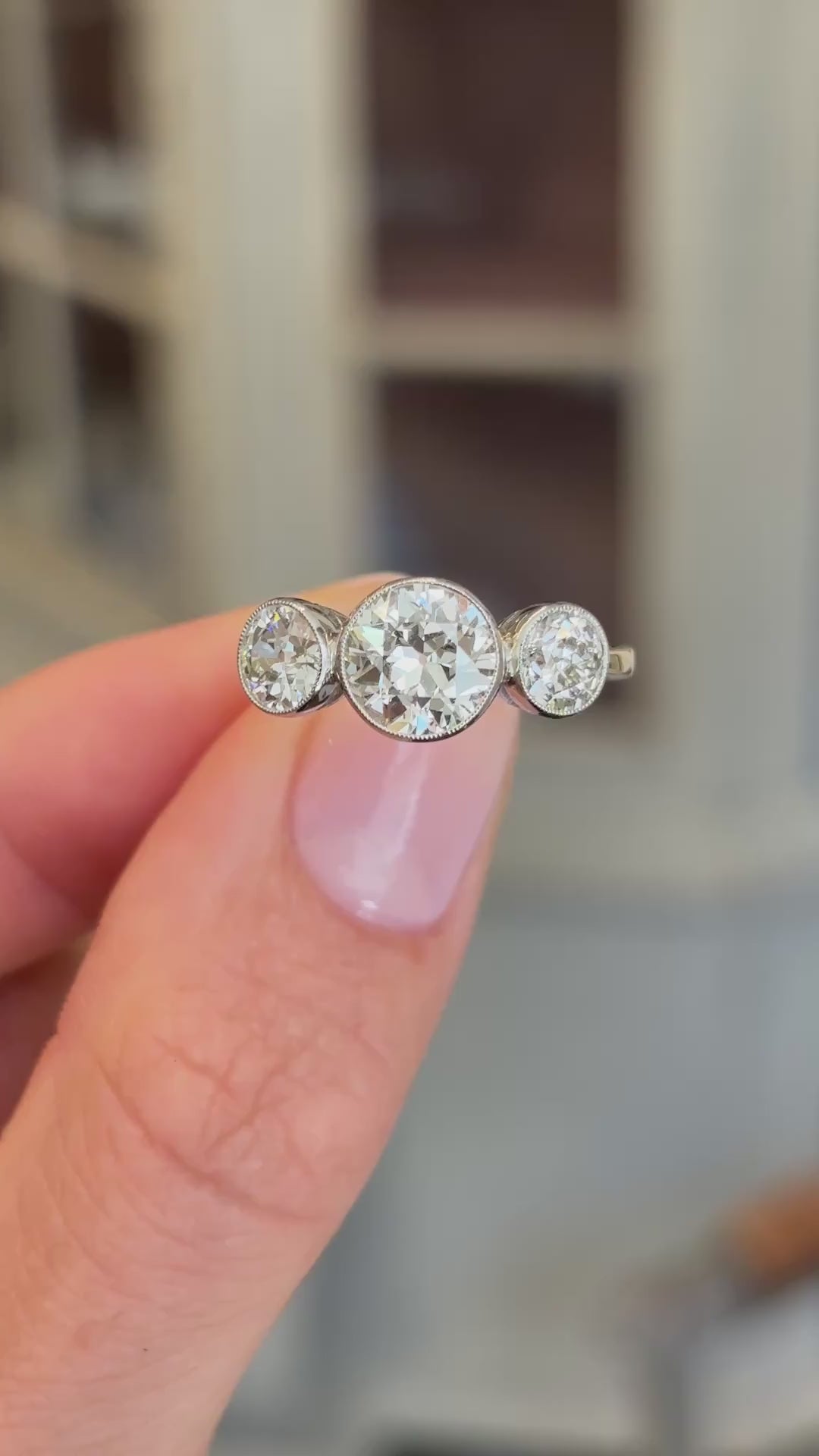 Antique Edwardian old-cut diamond three-stone engagement ring showcasing three old-cut diamonds, held by hand to highlight the setting and craftsmanship.