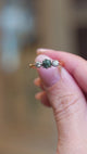 Close detail video of vintage 1950s green sapphire and diamond three-stone engagement ring shown between fingers.