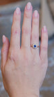 Antique Belle Époque sapphire and diamond cluster engagement ring worn on hand in motion.