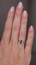 A video of an Antique-inspired, Emerald solitaire engagement ring being worn on a wedding finger, rotated slowly to show the profile of the setting once worn on the hand and the yellow gold band. 