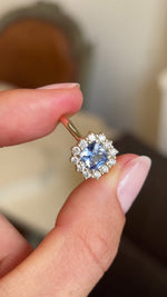 Video of an Antique-inspired, Cornflower-blue sapphire and diamond cluster engagement ring, showcasing the cushion-cut of the central sapphire and the yellow gold band. 