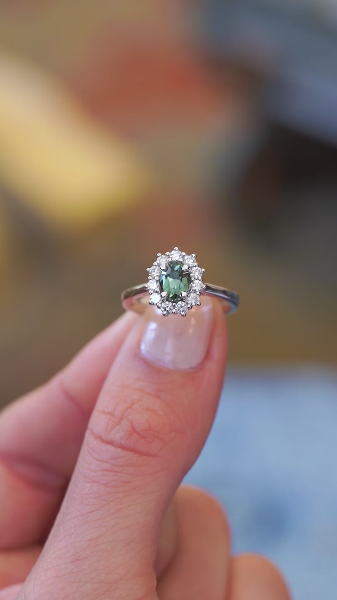 Sapphire and diamond cluster ring showing central green stone with surrounding sparkle.