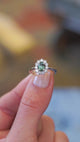 Sapphire and diamond cluster ring showing central green stone with surrounding sparkle.