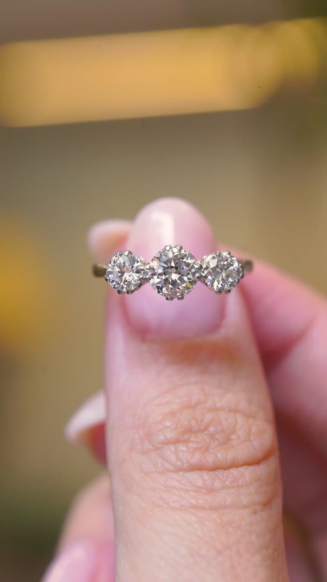 Video of Edwardian trilogy diamond ring held in between the fingers and turned.