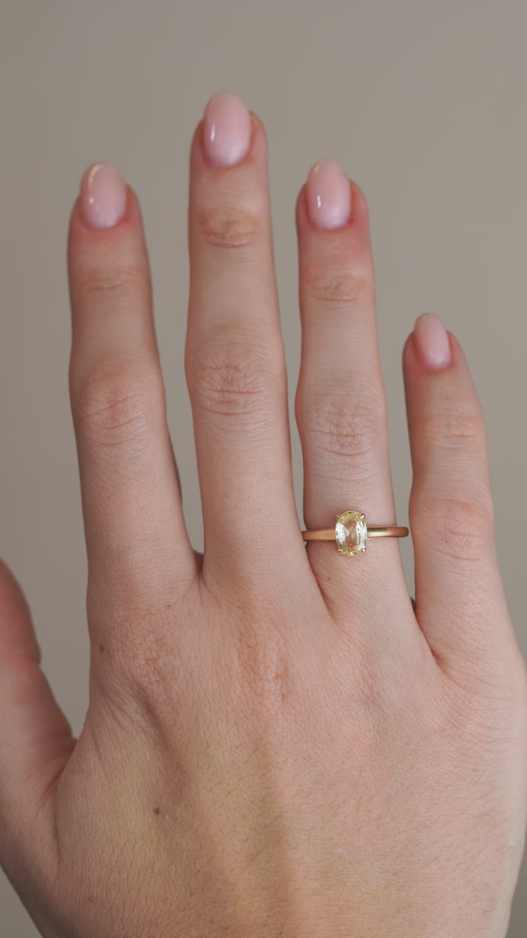 A video of the pale yellow sapphire ring worn on a finger, capturing the gemstone's gentle sparkle and classic solitaire design.