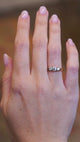 A hand showing an Edwardian three stone diamond ring with light movement.