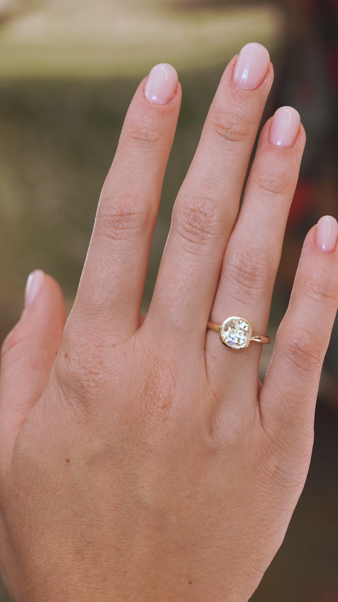 Video of a yellow-tinted old-mine cut diamond engagement ring worn on the hand, highlighting its antique-style facets and proportions.