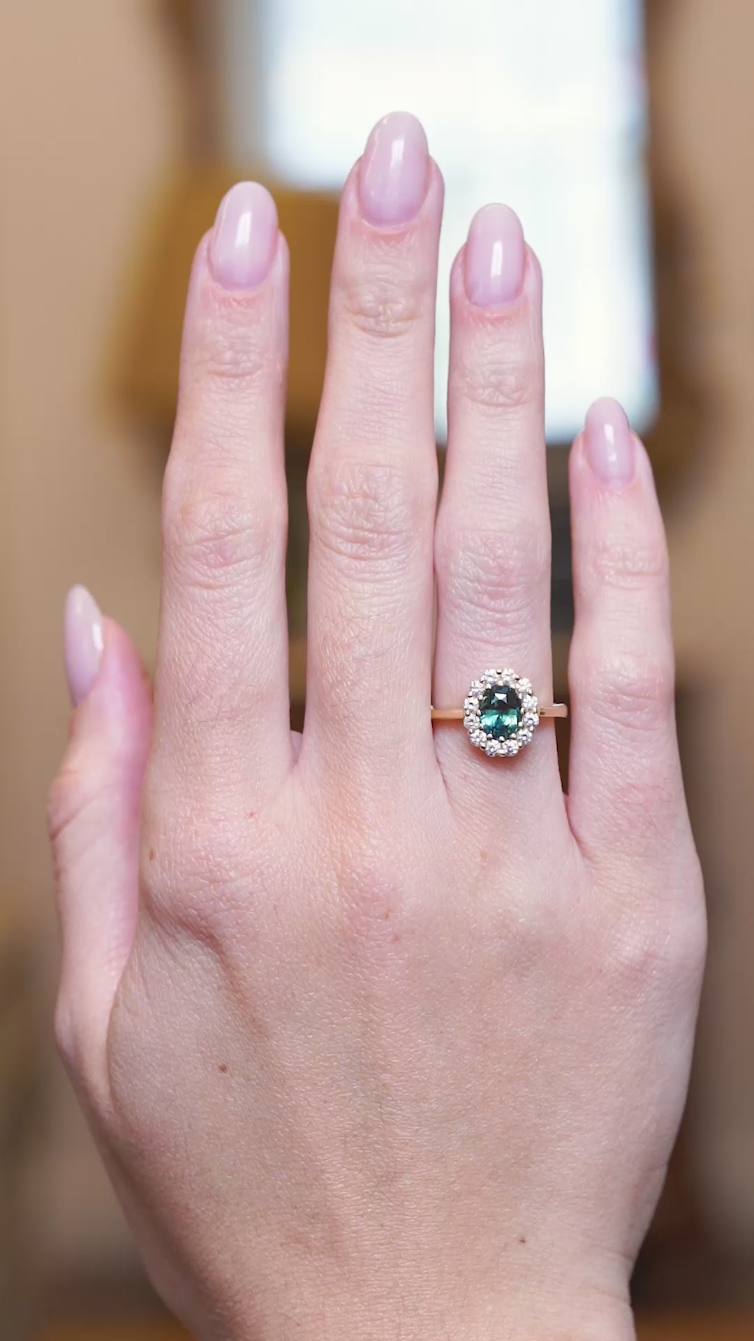 Antique inspired green sapphire and diamond cluster engagement ring worn on hand in motion.