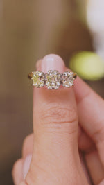 A video of a vintage diamond three-stone ring on a yellow gold band held between the fingers and slowly rotated to show off different angles of the ring.