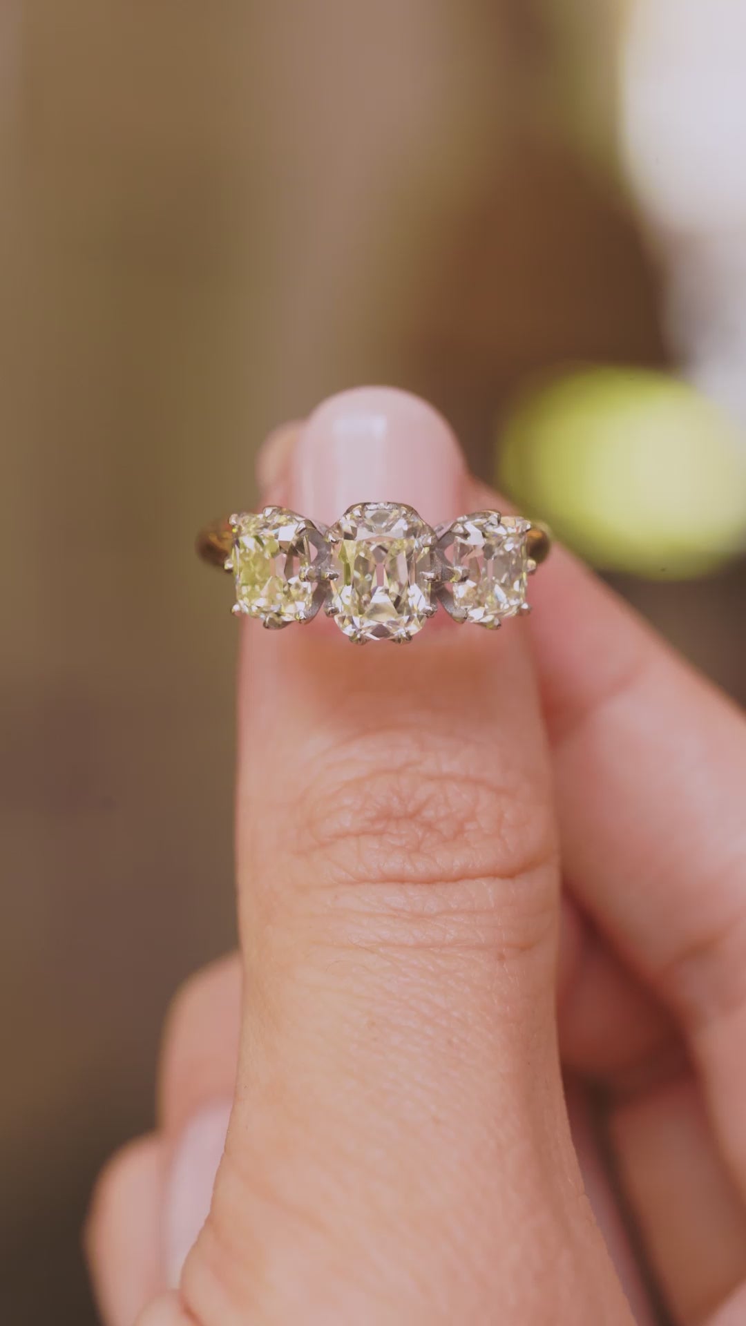 A video of a vintage diamond three-stone ring on a yellow gold band held between the fingers and slowly rotated to show off different angles of the ring.