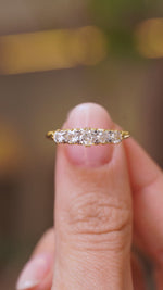 A close up video of an Antique, Victorian diamond five-stone engagement ring in yellow gold.  Held between two fingers and rotated slowly to display all the angles of the ring. 