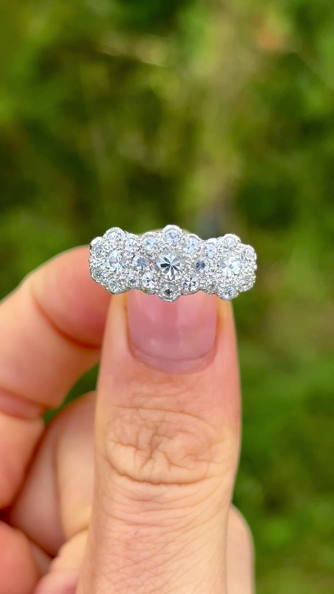 Vintage, 1970s cubic zirconia triple cluster ring held in fingers and rotated