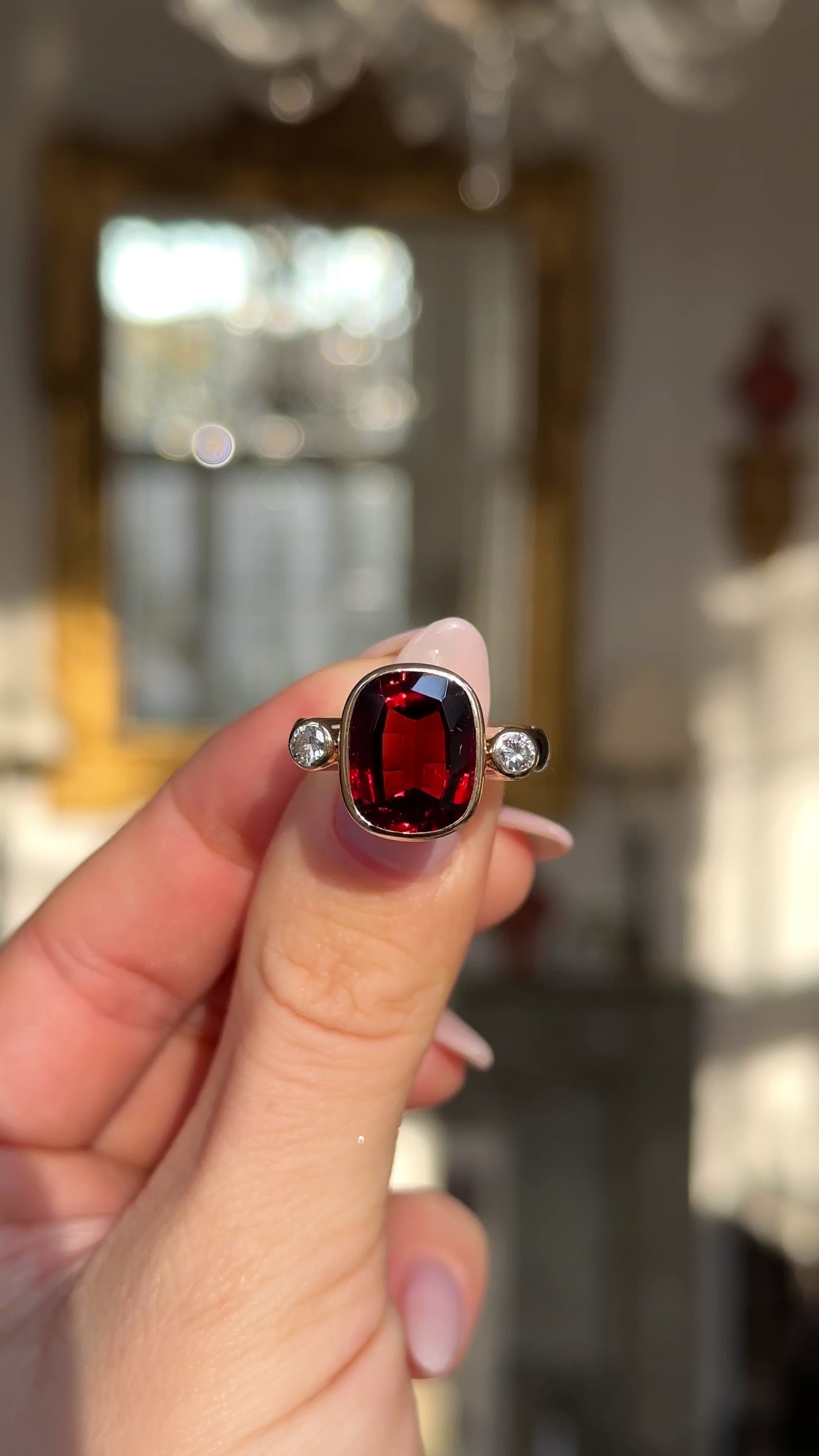 Vintage red zircon and diamond three stone ring held in fingers and moved around to give perspective.