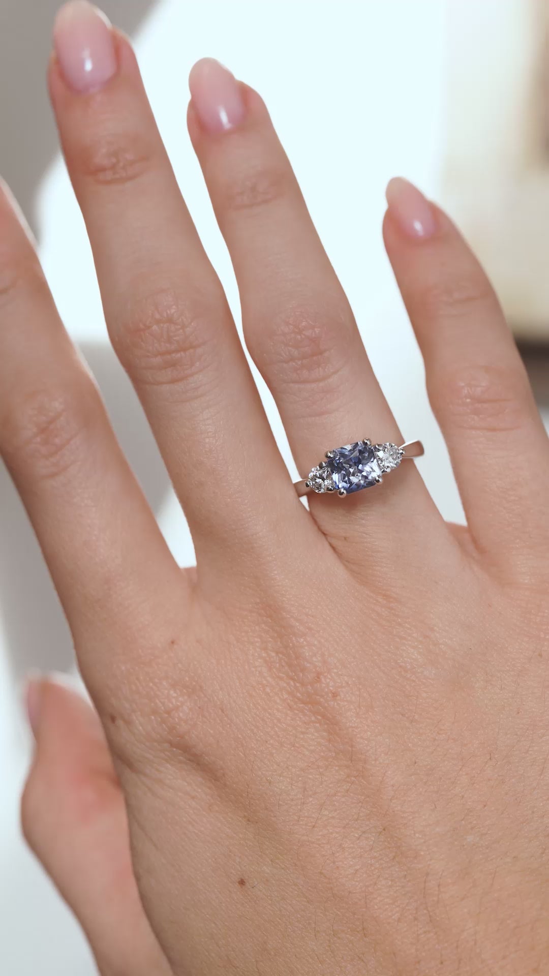A video of the sapphire and diamond engagement ring worn on a finger, capturing the gemstone's blue tones and sparkling diamond shoulders.