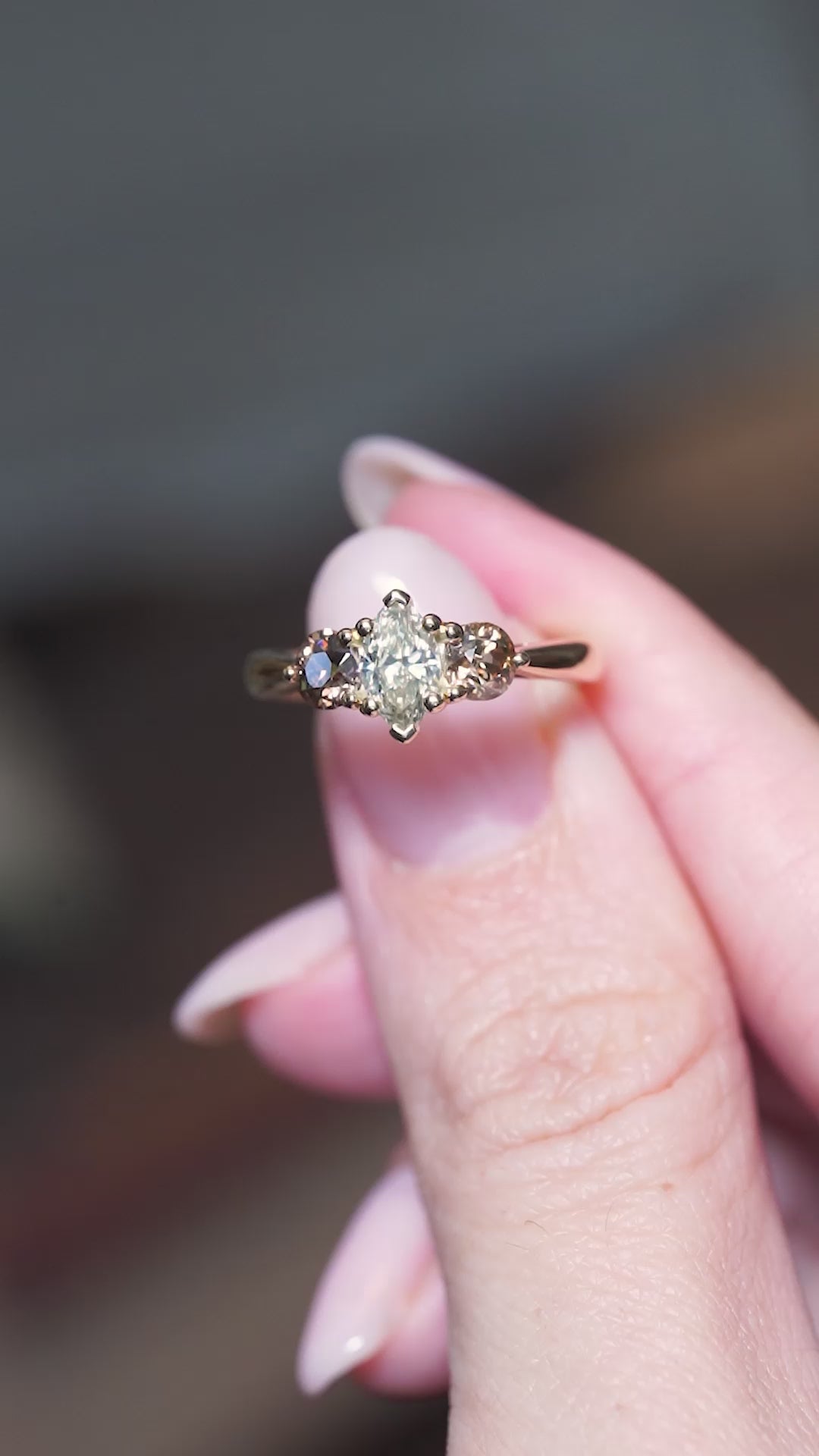 Diamond three-stone engagement ring held between fingers with movement to showcase the ring.