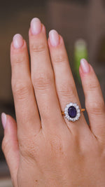 A video of a Vintage, 1940s deep blue sapphire and diamond cluster engagement ring worn on a wedding finger and rotated slowly to display the yellow gold band and profile of the ring once worn. 